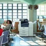 Xerox® Série VersaLink® B7100, imprimante monochrome en situation au travail Equipe au travail dans un Open space avec l'imprimante monochrome Xerox® Série VersaLink® B7100