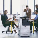 Xerox® Série VersaLink® C7100, imprimante multifonctions couleur en situation au travail Equipe de travail dans un bureau avec des papiers imprimés et l'imprimante multifonctions couleur Xerox® Série VersaLink C7100
